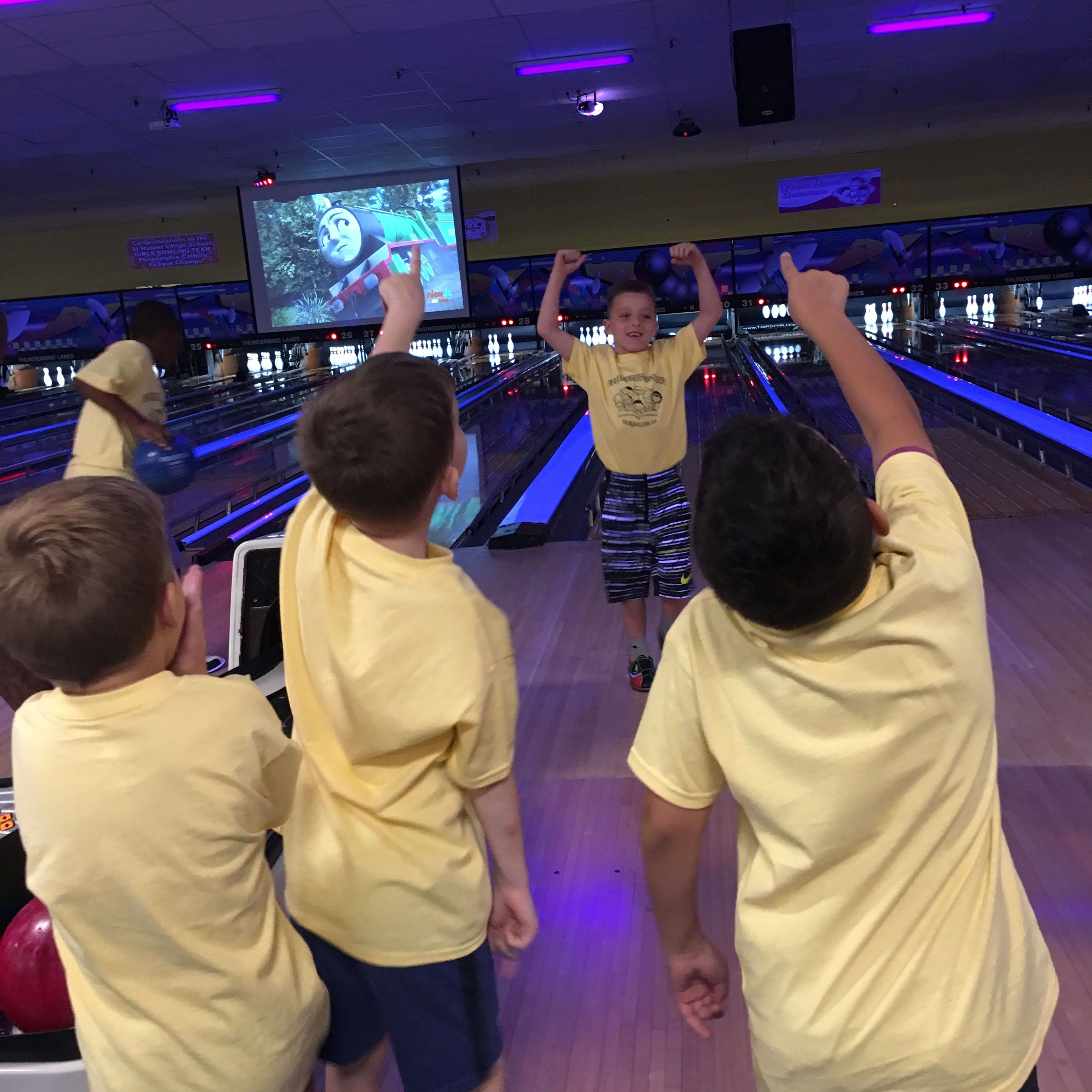 Young male students cheer on a classmate while bowling