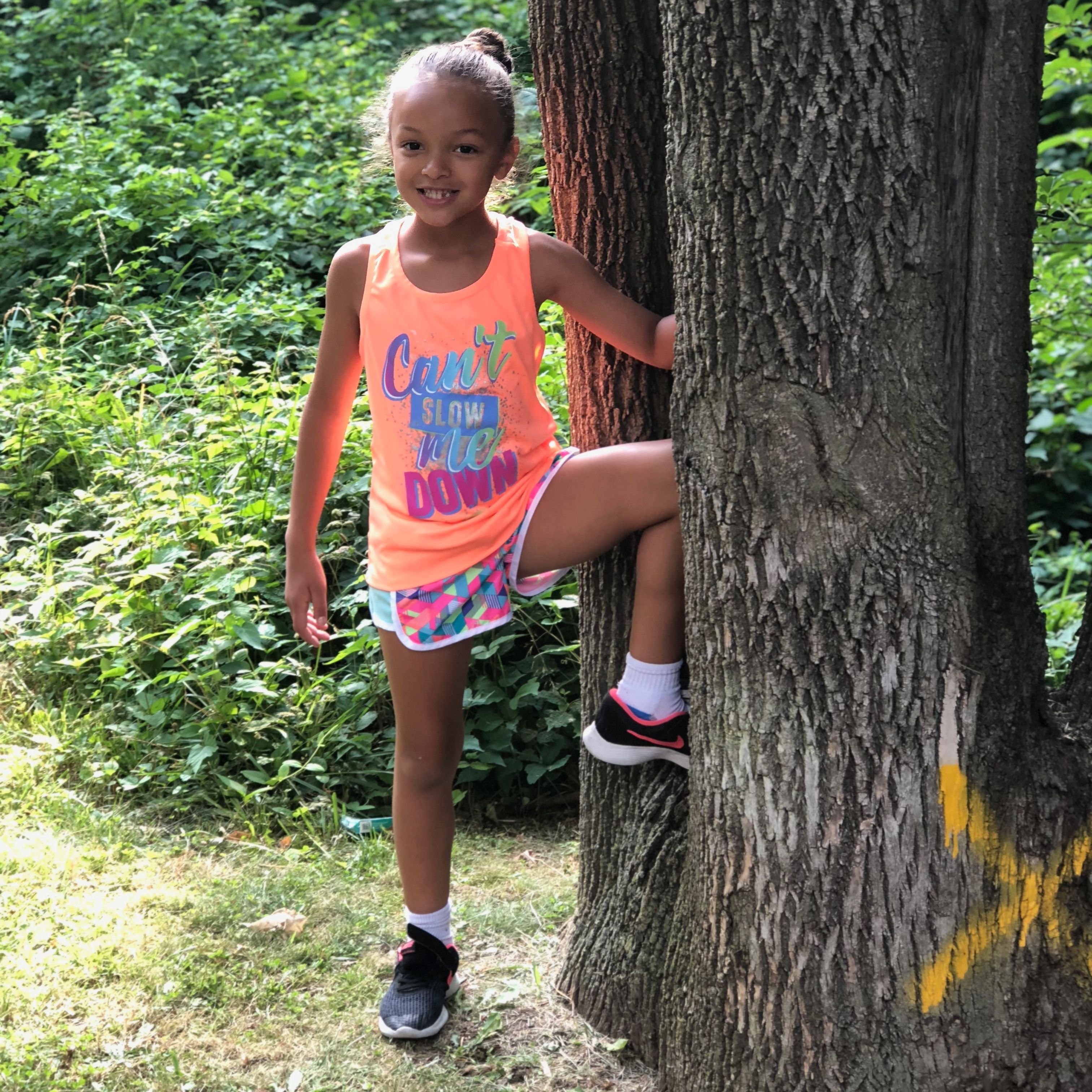 Young female student poses outdoors with a large tree