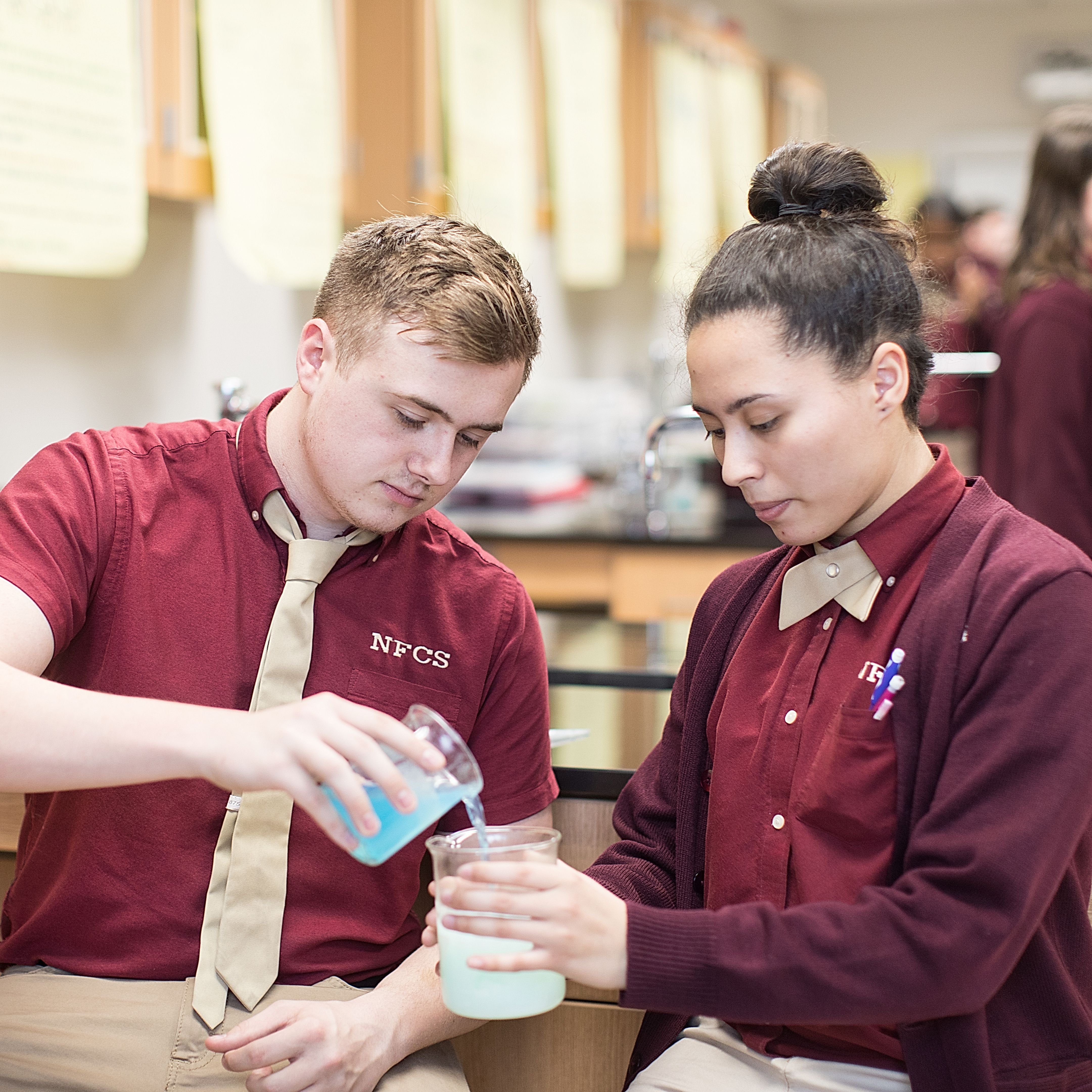  Male and female students mixing chemicals. 